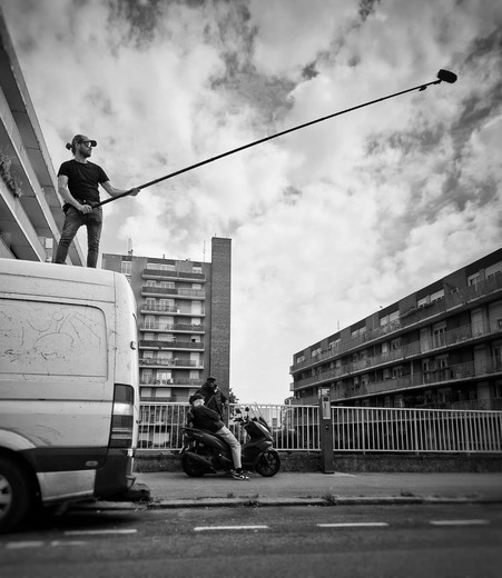Perchman sur le toit d'un camion de tournage dans une cité