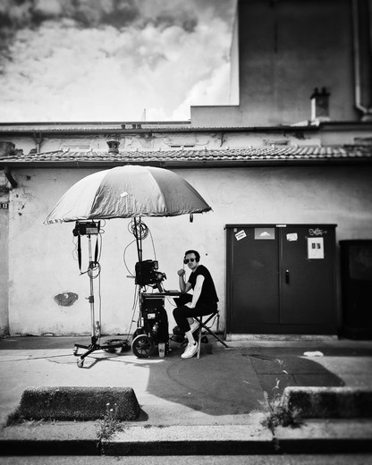 Chef opérateur du son assis sous un parapluie de protection, avec sa perche