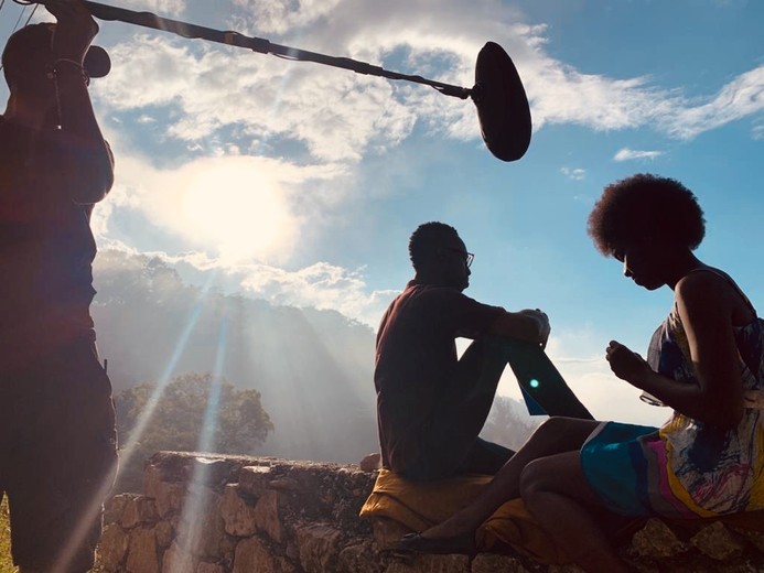 Équipe technique en contre-jour, avec une perche, lors d'un tournage en extérieur